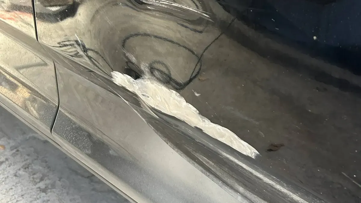 Raspón profundo en la puerta de una Maxus T60 negra antes de repararla