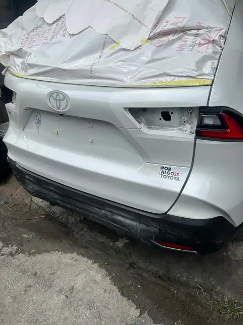 Parte trasera de un Toyota Yaris Cross blanco en proceso de pintura con papel protector.